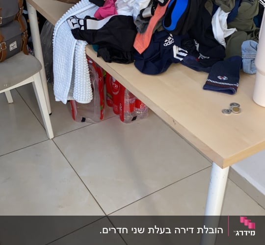בגדים ופריטים על שולחן, תיק גב, בקבוקי שתייה